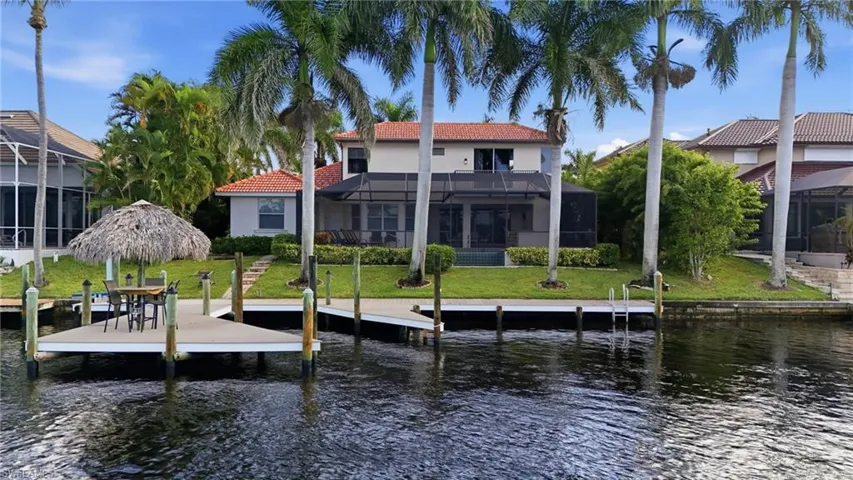 Dock with glass enclosure, a sunroom, a water view, and a lawn