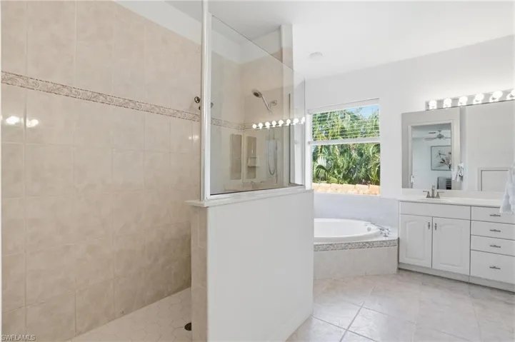 Bathroom with walk in shower, vanity, a bath, and light tile patterned floors