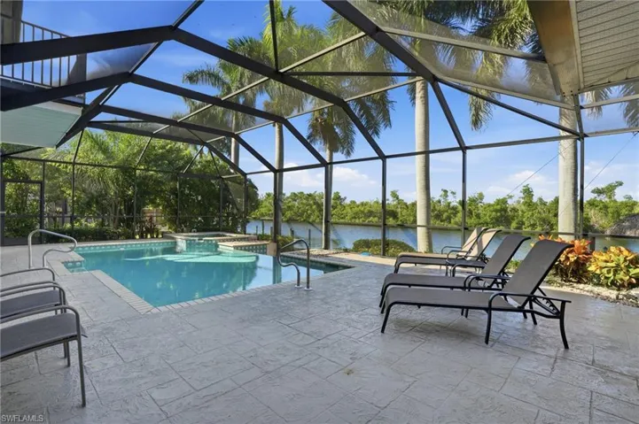 View of swimming pool with a lanai, a patio area, a water view, and a sunroom