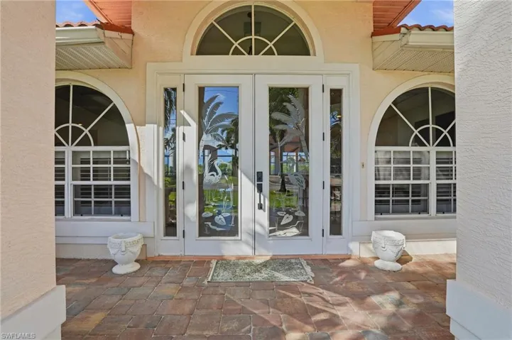 Doorway to property featuring a tile roof, a patio area, and stucco siding