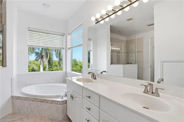 Full bathroom with a bath, double vanity, walk in shower, and light tile patterned floors