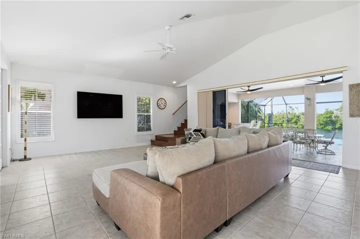 Living area featuring healthy amount of natural light, ceiling fan, light tile patterned floors, and high vaulted ceiling