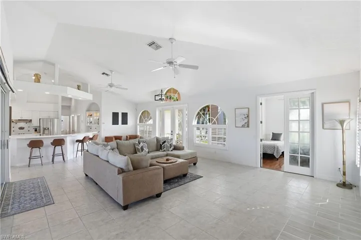 Living room featuring french doors, high vaulted ceiling, and a ceiling fan