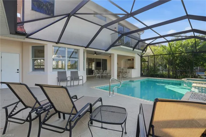 View of swimming pool featuring a patio area, a sunroom, glass enclosure, a pool with connected hot tub, and a ceiling fan