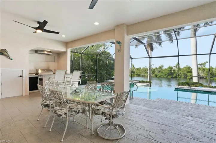 Dining area with a sunroom, ceiling fan, recessed lighting, stone tile flooring, and a water view
