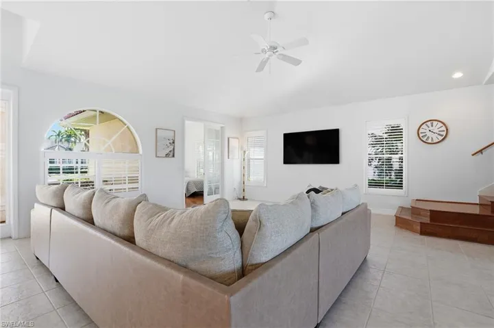 Living room with light tile patterned floors, a ceiling fan, recessed lighting, and stairs