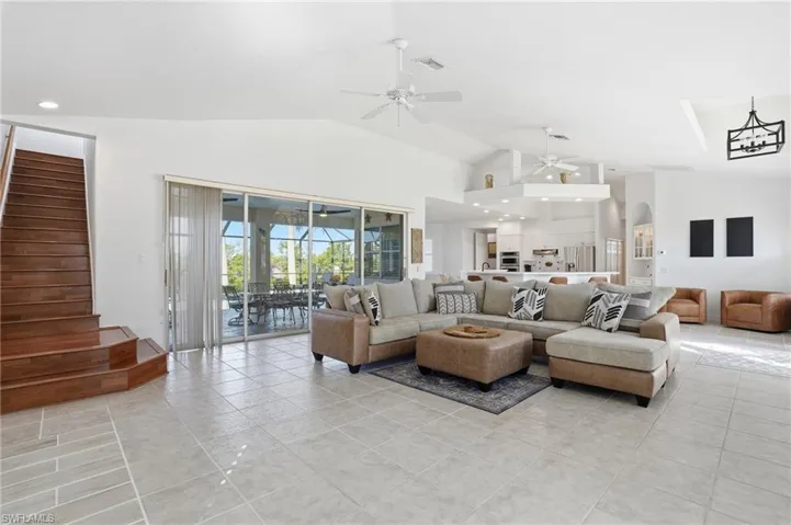 Living area featuring light tile patterned floors, arched walkways, and high vaulted ceiling
