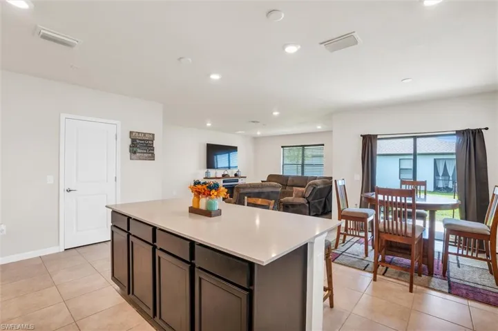Kitchen featuring recessed lighting, light countertops, a kitchen island, light tile patterned flooring, and a kitchen bar