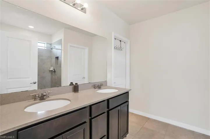 Bathroom featuring double vanity, a tile shower, and tile patterned flooring