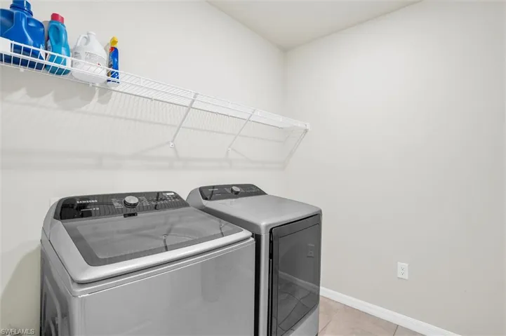 Laundry room with washing machine and clothes dryer and light tile patterned flooring