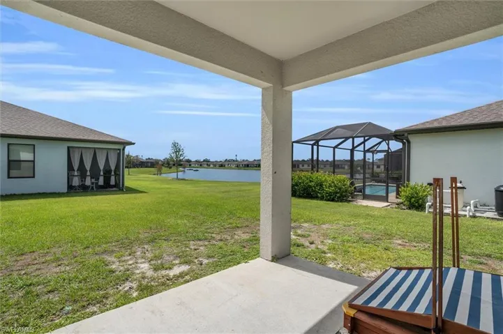 View of green lawn featuring a water view, a patio area, glass enclosure, and an outdoor pool
