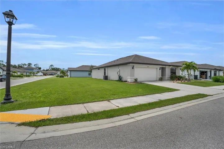 View of front of home with a garage, stucco siding, a front lawn, driveway, and a residential view