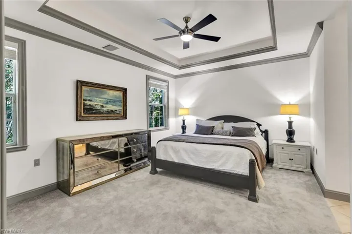 Bedroom with visible vents, light carpet, a tray ceiling, and crown molding