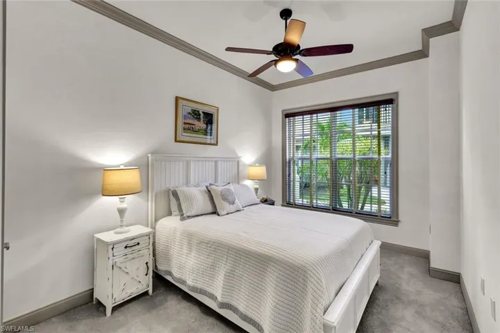 Bedroom with light colored carpet, crown molding, and baseboards