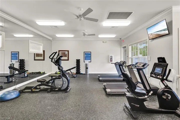Workout area featuring visible vents, ornamental molding, and a ceiling fan