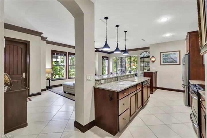 Kitchen with appliances with stainless steel finishes, arched walkways, a sink, and light tile patterned floors