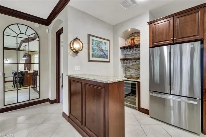 Kitchen featuring open shelves, light tile patterned flooring, beverage cooler, freestanding refrigerator, and visible vents