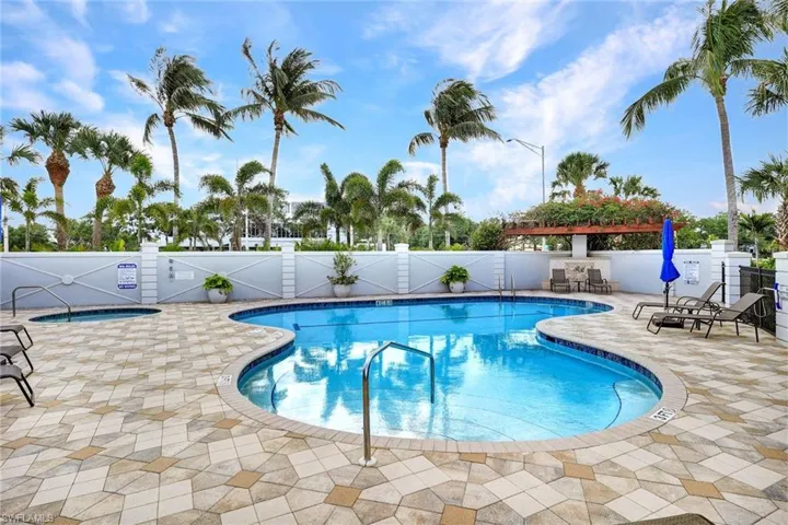 Community pool with a fenced backyard, a hot tub, and a patio