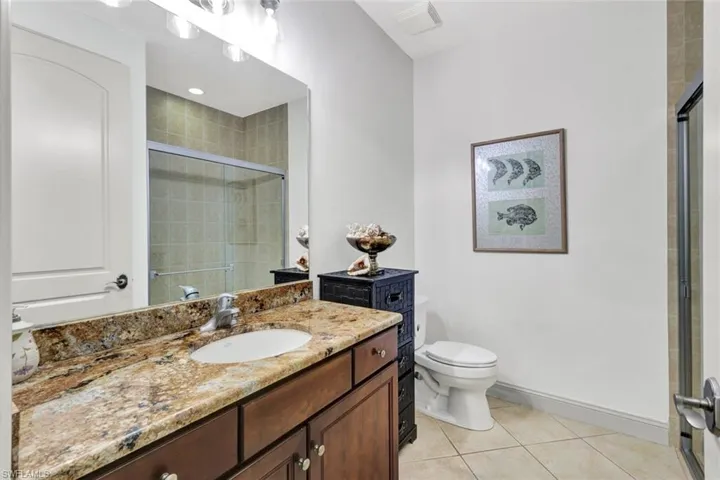 Full bath featuring tile patterned flooring, vanity, toilet, baseboards, and a shower stall