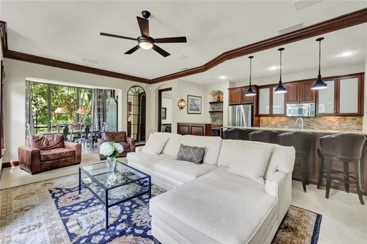 Living area with light tile patterned floors, a ceiling fan, ornamental molding, and visible vents