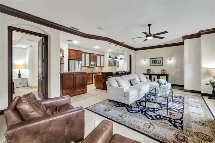 Living area with light tile patterned floors, baseboards, arched walkways, visible vents, and a ceiling fan
