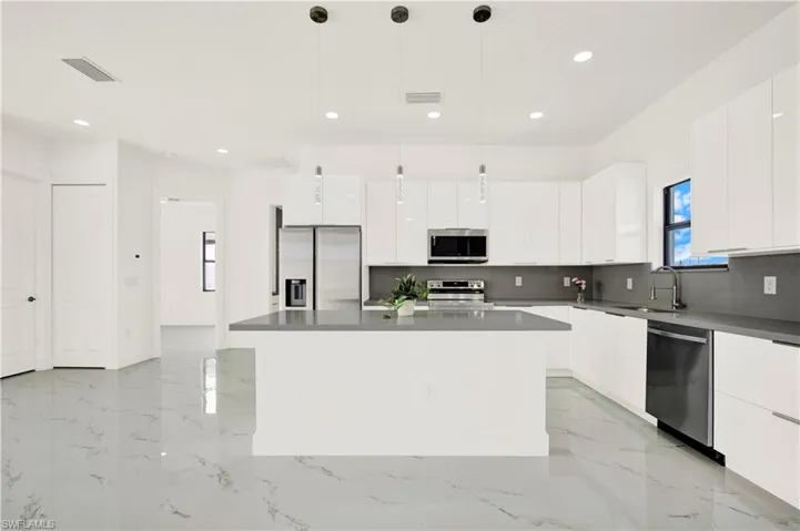 Kitchen with stainless steel appliances, modern cabinets, white cabinetry, and plenty of natural light