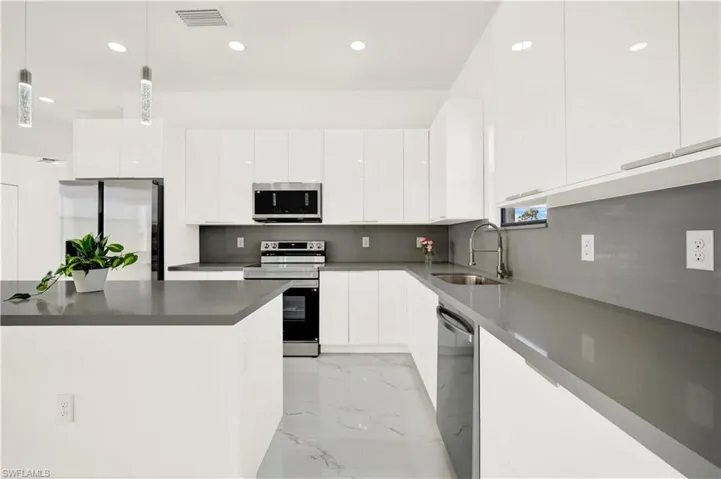 Kitchen with stainless steel appliances, white cabinetry, modern cabinets, and hanging light fixtures