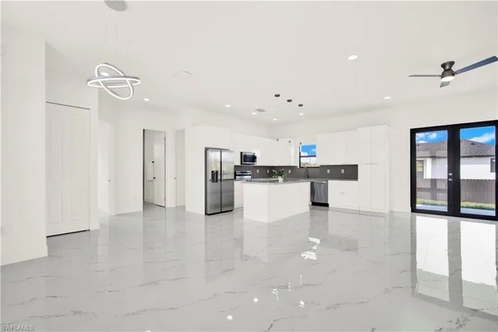 Kitchen featuring open floor plan, decorative light fixtures, stainless steel appliances, a center island, and white cabinets