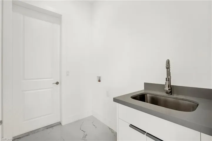 Laundry room with light marble finish flooring, hookup for a washing machine, and cabinet space
