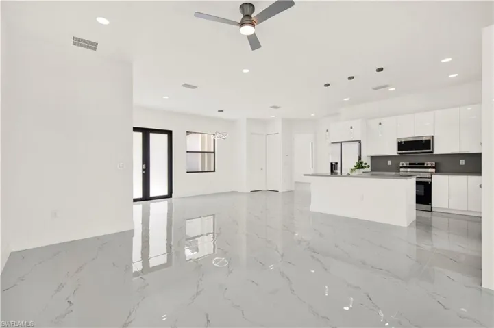 Unfurnished living room with a ceiling fan, recessed lighting, and light marble finish flooring