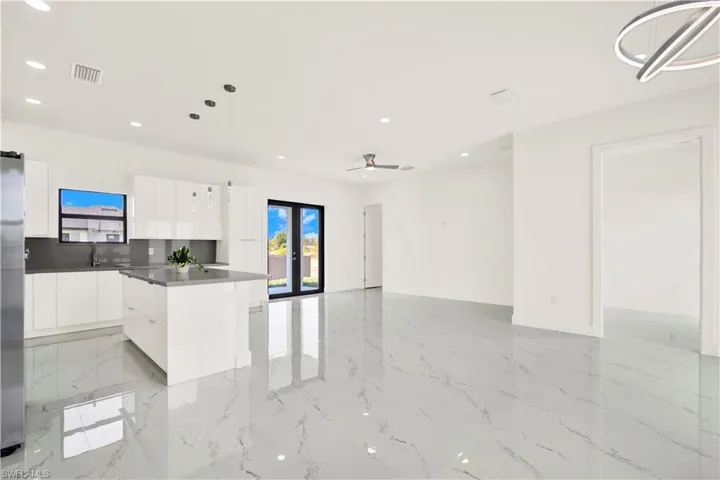 Kitchen with pendant lighting, a kitchen island, modern cabinets, white cabinets, and open floor plan