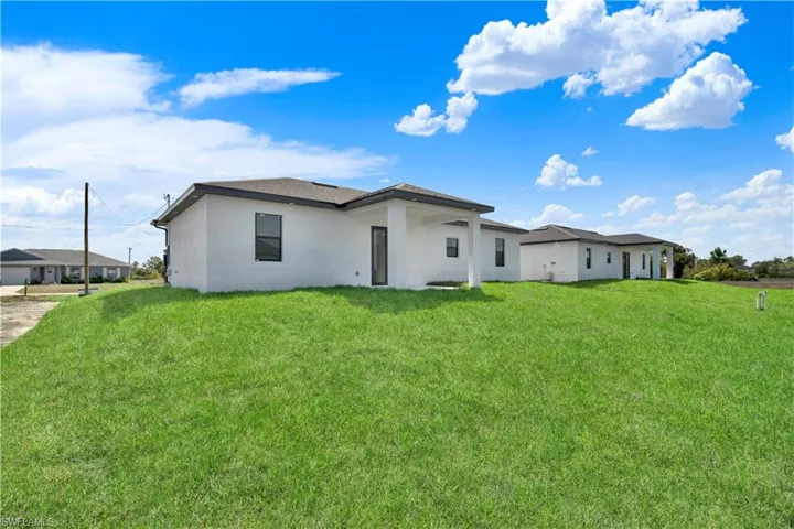 Rear view of house featuring stucco siding and a lawn