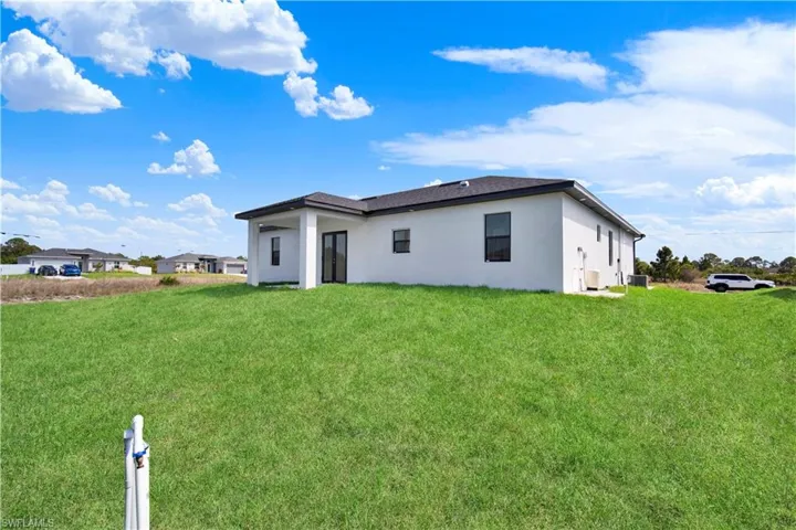 Rear view of property with stucco siding and a lawn