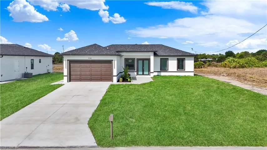 Prairie-style home with a front lawn, stucco siding, driveway, a garage, and french doors