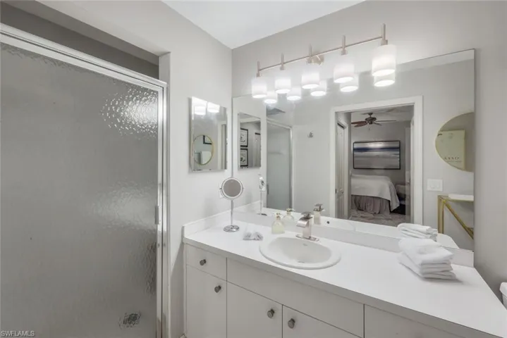 Ensuite bathroom with a stall shower, vanity, and ceiling fan