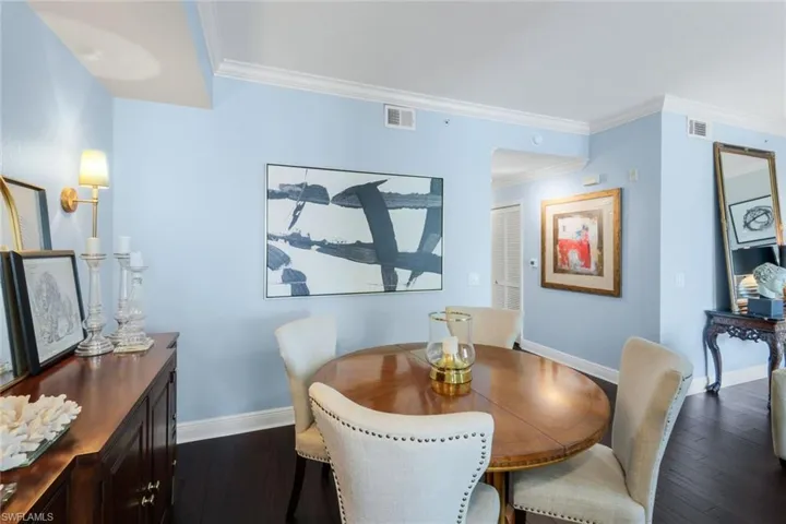 Dining room featuring dark wood finished floors and crown molding