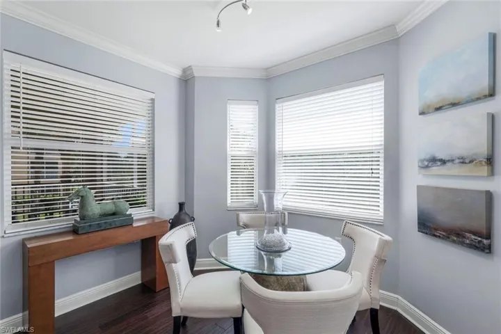 Dining space with crown molding, healthy amount of natural light, and dark wood-type flooring