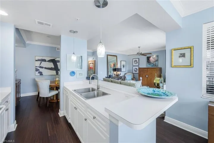 Kitchen with crown molding, white cabinets, light countertops, hanging light fixtures, and a ceiling fan