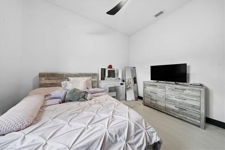 Bedroom with light wood-style floors, a ceiling fan, and vaulted ceiling