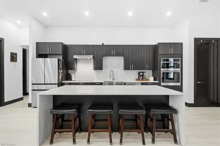 Kitchen with a kitchen breakfast bar, backsplash, appliances with stainless steel finishes, a center island, and recessed lighting