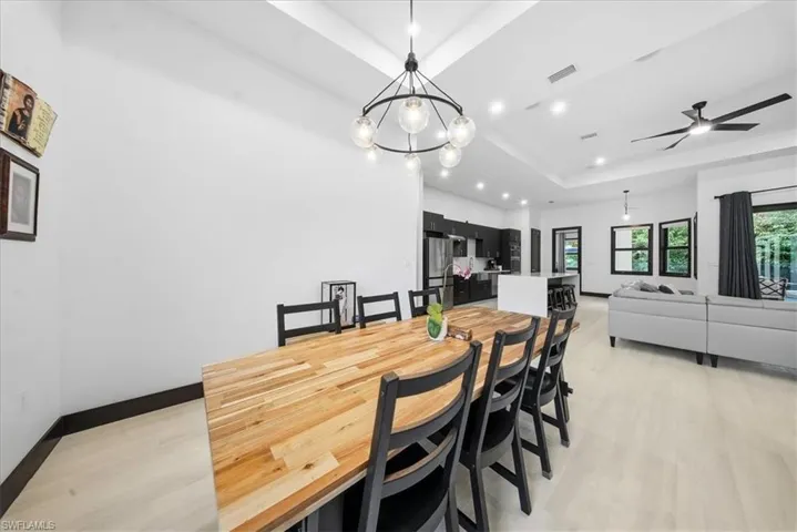 Dining room with a raised ceiling, a chandelier, light wood-type flooring, and recessed lighting