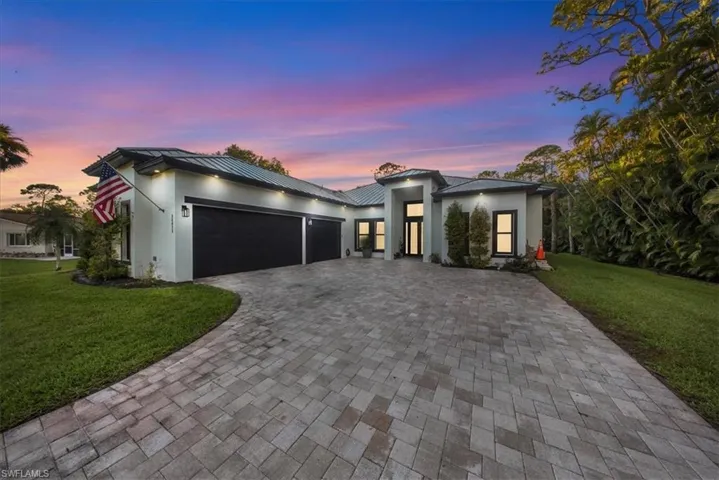 Contemporary home featuring a lawn, a garage, decorative driveway, a metal roof, and stucco siding