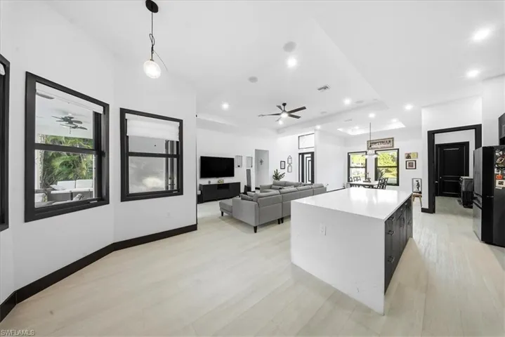 Kitchen featuring dark cabinets, hanging light fixtures, freestanding refrigerator, a center island, and open floor plan