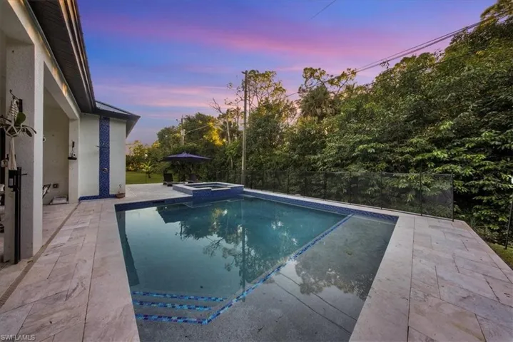 Pool at dusk featuring a patio and a pool with connected hot tub