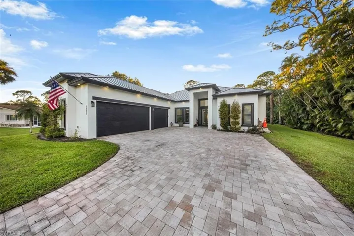 Prairie-style house with a front lawn, a garage, stucco siding, and decorative driveway