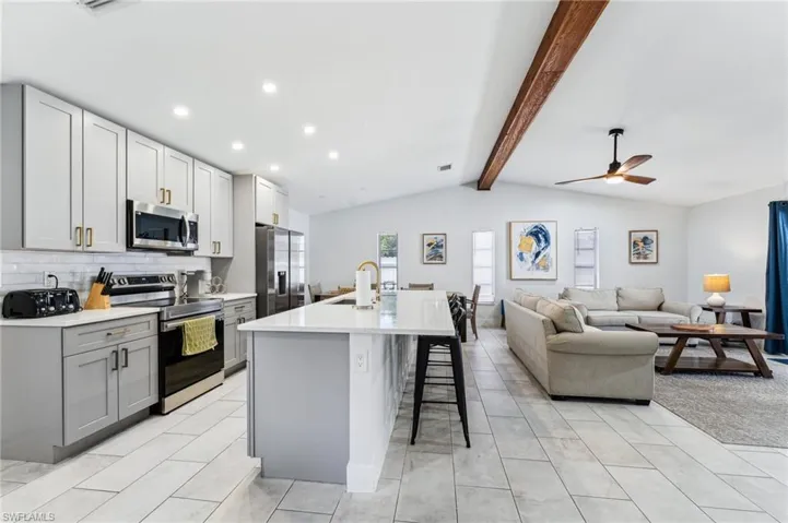 Kitchen with stainless steel appliances, a sink, a kitchen breakfast bar, light countertops, and recessed lighting