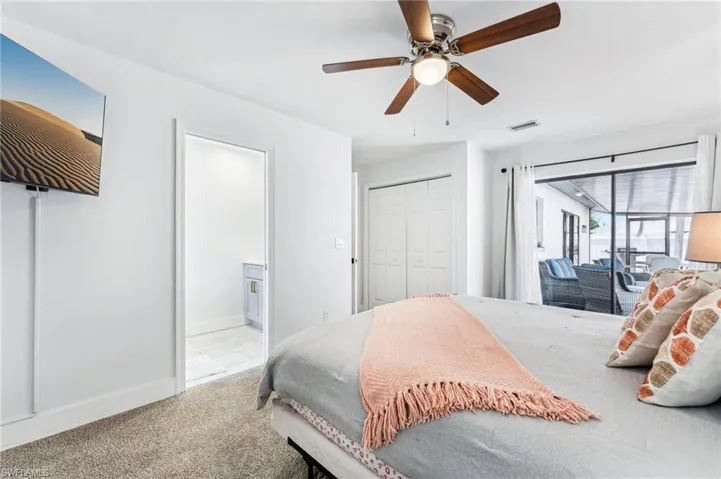 Carpeted bedroom featuring access to exterior, a closet, a ceiling fan, baseboards, and connected bathroom