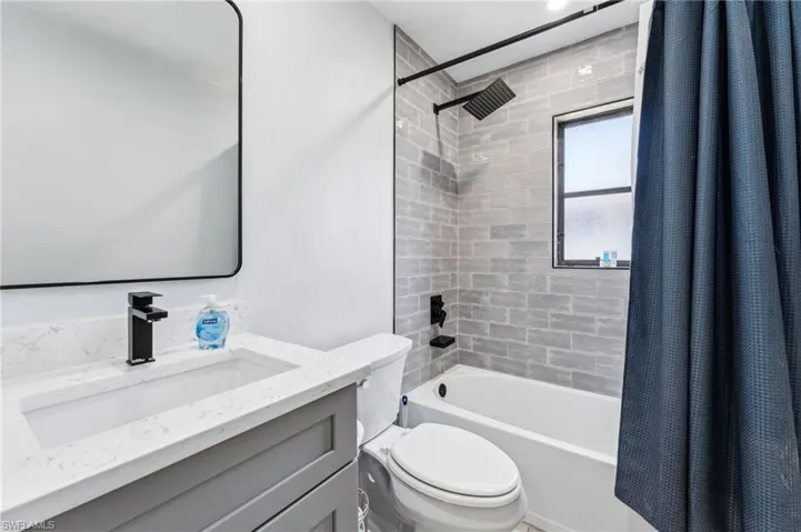 Bathroom featuring toilet, shower / bath combination with curtain, and vanity