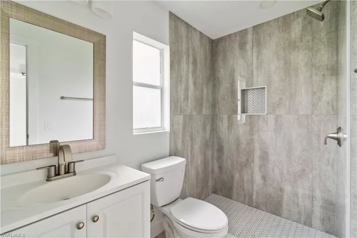 Bathroom featuring walk in shower, vanity, and toilet