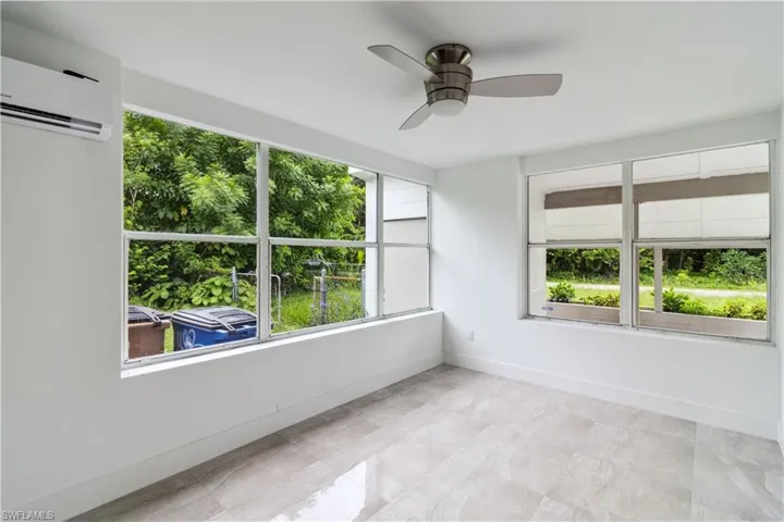 Unfurnished sunroom with ceiling fan and a wall unit AC
